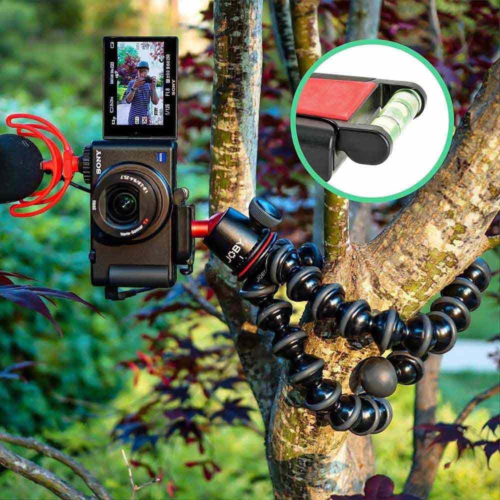 Camera mounted on a flexible tripod with a microphone and screen displaying video, all attached to a tree.