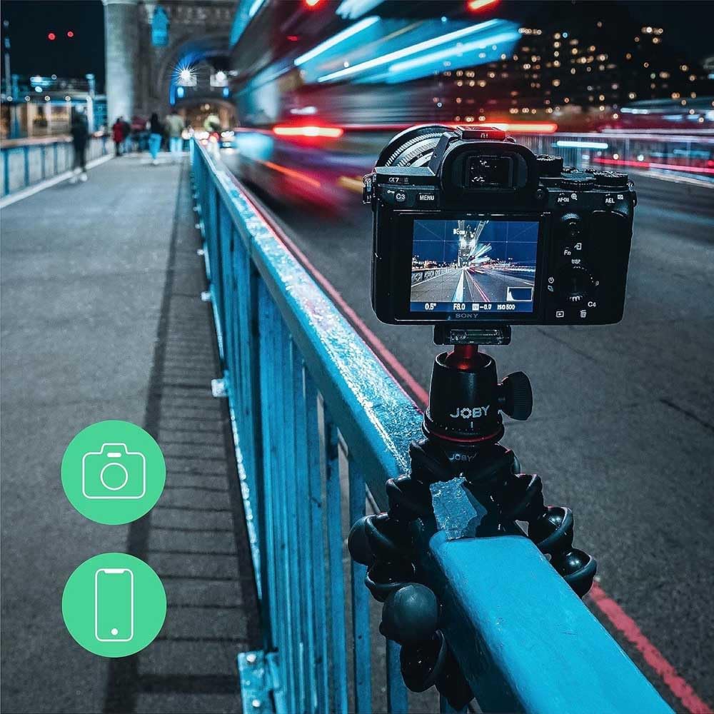 Camera on a tripod capturing a city street at night with blurred lights