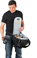 Man holding a camera bag with a camera inside on a white background