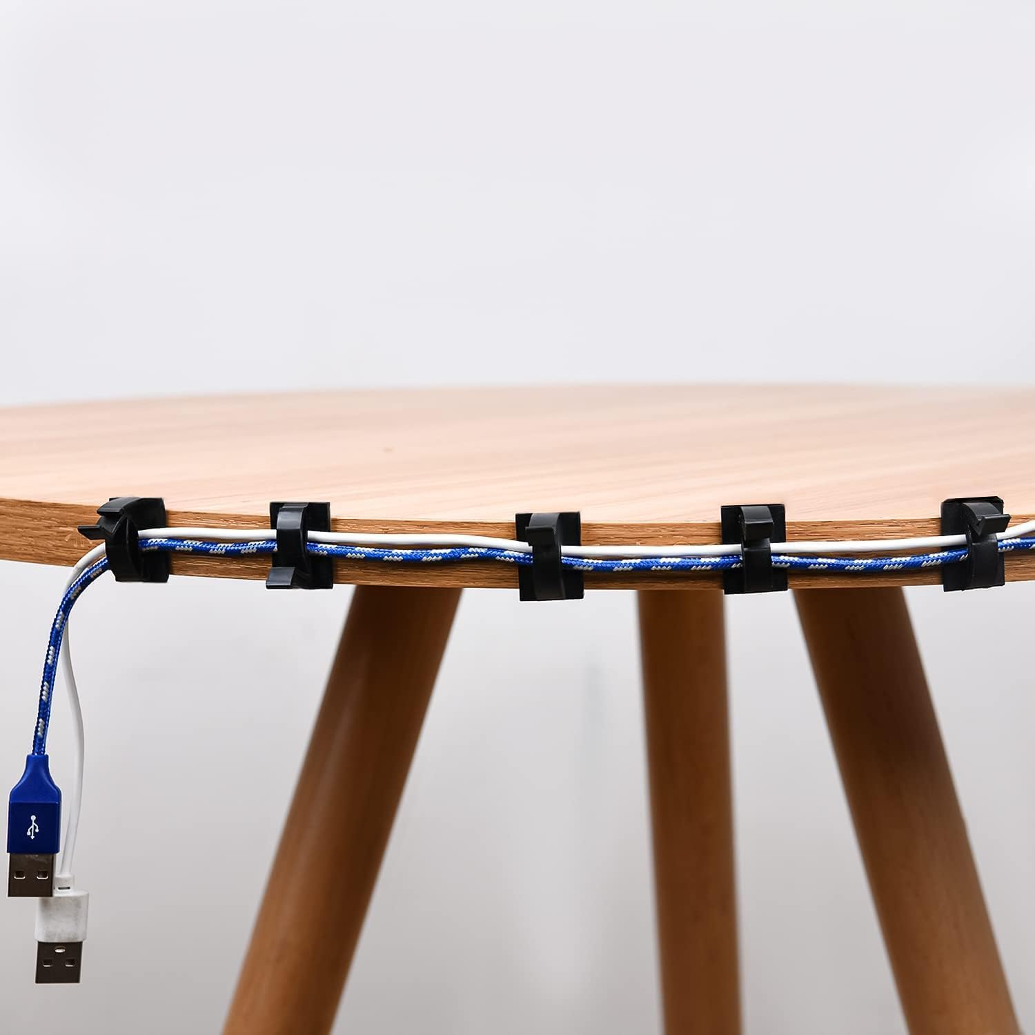 Wooden stool with blue cable managed using black clips on a white background