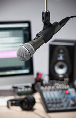 Microphone on a stand with audio equipment in the background