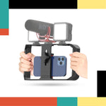 Phone holder with camera and microphone attachments held by hands on a colorful background