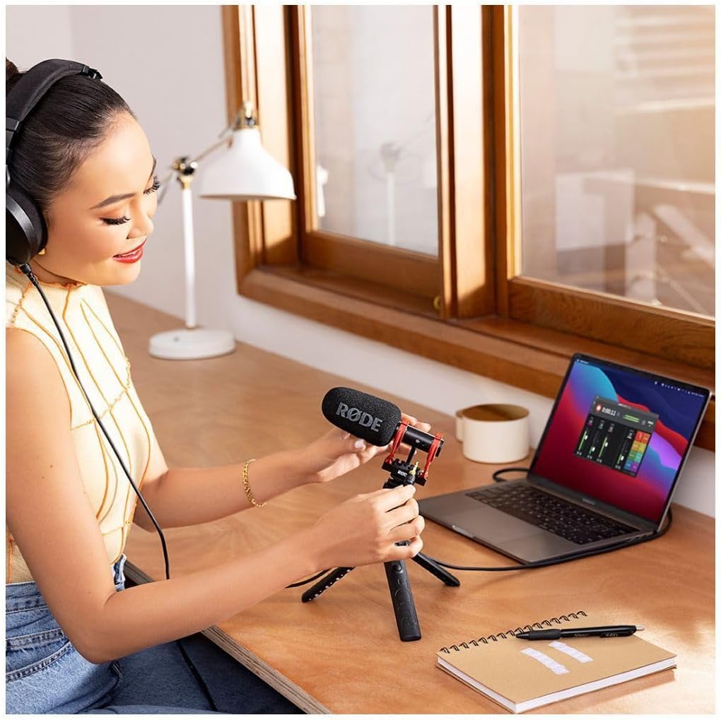 Woman recording a video with a microphone and laptop on a desk.