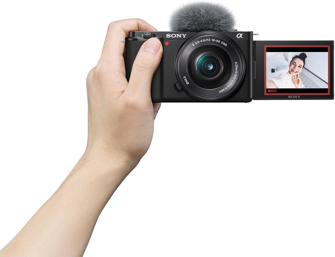 Hand holding a Sony camera with microphone attachment on a white background